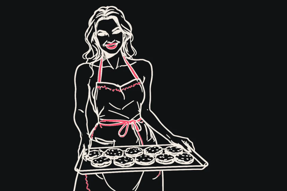 A woman in an apron holds a tray of cookies